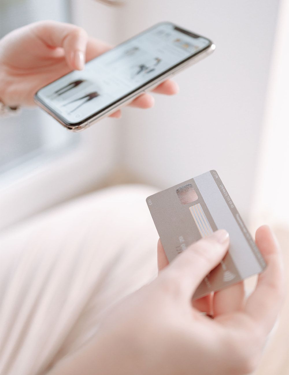 Un téléphone affichant une boutique en ligne dans une main, une carte bancaire dans l'autre