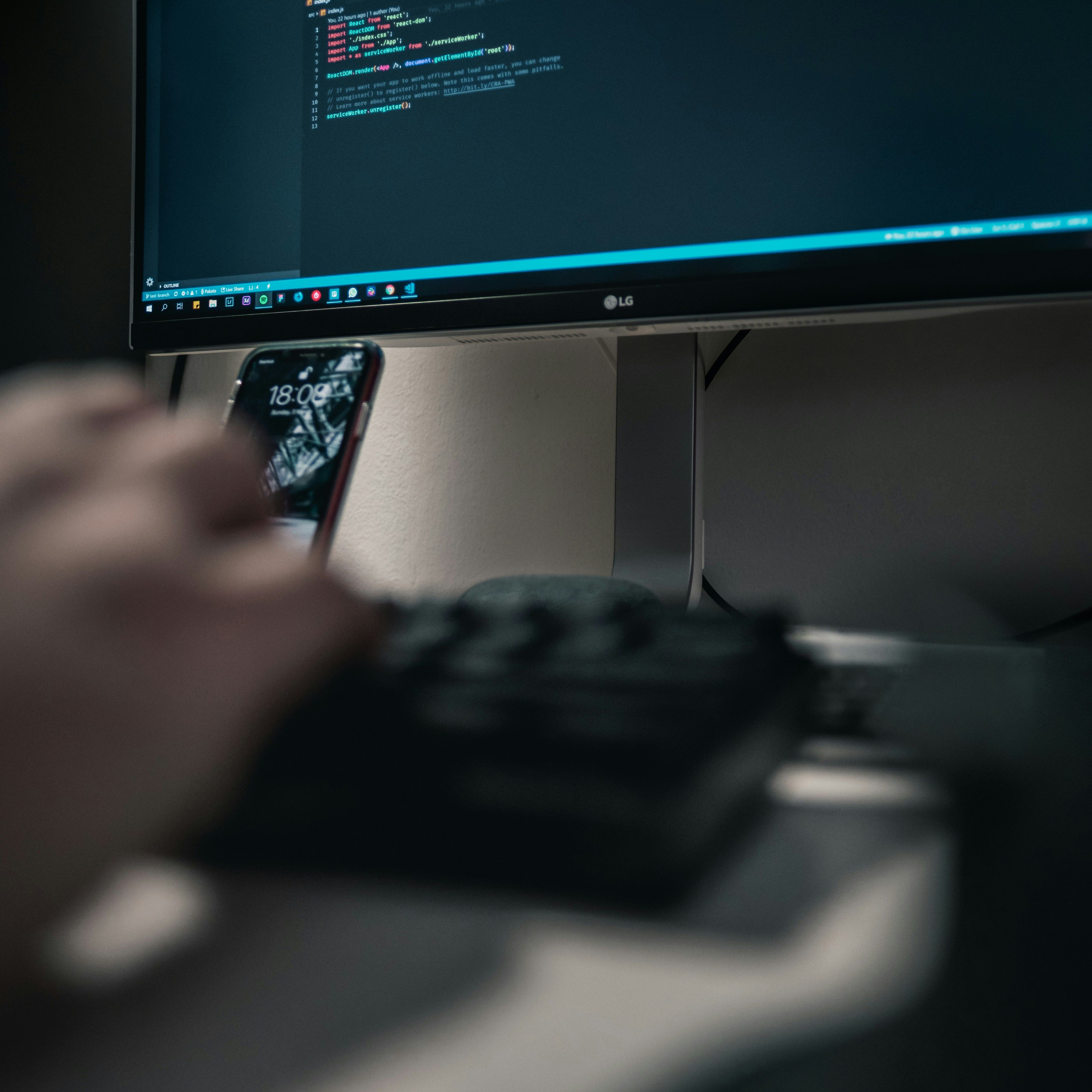 Lignes de code affichées sur un écran large, clavier au premier plan
